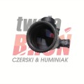 Okular lunety Meopta ZD 6-24x56 Z-plus RD z bliska, widoczne fioletowe warstwy antyrefleksyjne i zarys wieżyczek w tle.