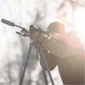 Trójnóg Primos Trigger Stick Apex - zdjęcie zimowe, myśliwy celujący z karabinu z tłumikiem opartego na trójnogu, pod słońce