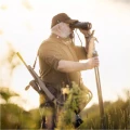 Trójnóg Primos Trigger Stick Gen III™ 24-62'' - zdjęcie w plenerze, myśliwy obserwujący okolicę przez lornetkę, opierając rękę o trójnóg