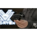 Celownik pryzmatyczny Vortex Spitfire AR 1x Prism Scope w dłoni mężczyzny, z logo Vortex w tle