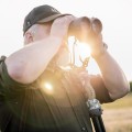 Lornetka Vortex Diamondback HD 15x56 przy oczach mężczyzny, trzymana w obu dłoniach