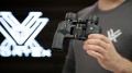 Lornetka Vortex Raptor 10x32 w ręku mężczyzny, z logo w tle