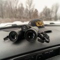 Lornetka Vortex Triumph HD 10x42 na kokpicie w samochodzie, z czapką z daszkiem w tle