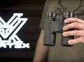 Lornetka Vortex Viper HD 10x42 w dłoni mężczyzny, z logo Vortex w tle