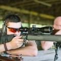 Luneta celownicza Primary Arms Classic 3-9x44 mm SFP Duplex, 30 mm - myśliwy celujący z broni z nowoczesną lunete celownicza na  tle altany