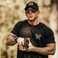 Kolimator Vortex Defender-CCW Solar 3 MOA na broni w obu dłoniach mężczyzny