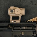 Zbliżenie na kolimator Vortex Crossfire II Solar Red Dot Tan z czerwonym punktem 2 MOA, zamocowany na broni w kolorze piaskowym.