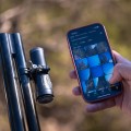 Strzelecka kamera sportowa na broń HIKMICRO HIKCam A7E zamontowana na broni oraz smartfon z aplikacją do podglądu i zarządzania nagraniami w terenie.