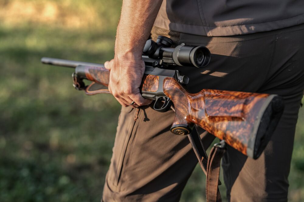 Sig Sauer 505 - myśliwy trzymający karabinek z lunetą, widok na kolbę z drewna orzechowego