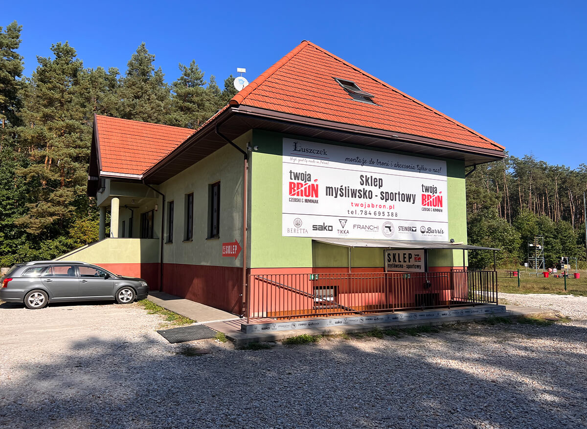 Twoja Broń - siedziba sklepu myśliwsko-sportowego, budynek z parkingiem i tablicą marek